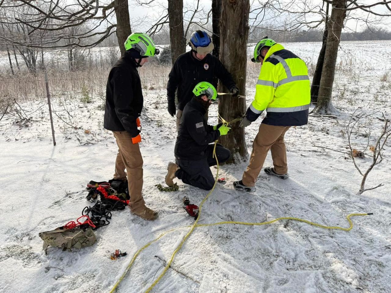 Rescue Squad members using a rope system to help EMS move a patient across a snow-covered, frozen driveway